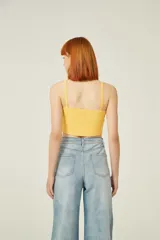 Top amarillo de breteles finos, confeccionado en poliéster de punto canalé, corte al cuerpo, con botones y cuello en V.