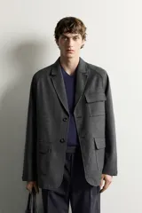 Blazer regular fit de color gris oscuro, confeccionado en tejido con estructura, con cuello de solapas de muesca, cierre frontal con botones y bolsillos plastrón con solapa en el delantero.