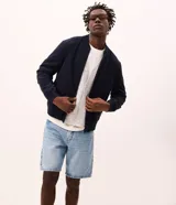 Campera tipo bomber masculina de color beige, con cuello, puños y ruedo acanalados. Presenta cierre frontal por cremallera, bolsillos laterales y acabado con tecnología repelente al agua.