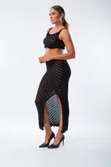 Pollera midi de tejido de punto calado en color negro, con diseño de rayas diagonales y tajo lateral profundo.