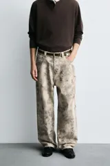 Pantalón de corte relajado confeccionado en algodón, con diseño de efecto lavado y estampado abstracto en tonos grises y beige. Presenta cinco bolsillos y cierre frontal con cremallera y botón.