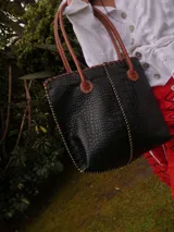 Bolso shopper de cuero azul con textura crocco, manijas largas marrones y costuras artesanales visibles en los bordes.