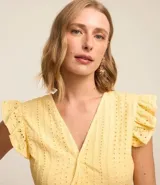 Blusa amarilla sin mangas confeccionada en laise con cuello V, volados en los hombros y recorte fruncido en la cintura.