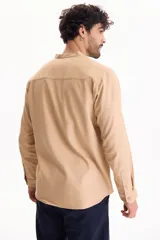 Camisa de manga larga color beige con cuello mao y cierre frontal con botones.