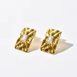 Par de caravanas doradas con forma rectangular y textura irregular. Cuentan con un cristal rectangular en el centro.