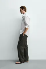 Camisa de corte regular fit color blanco, confeccionada en tejido de algodón con efecto arrugado, con cuello solapa, manga larga, puños abotonados y un bolsillo de parche en el pecho.