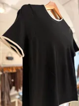 Remera tejida de manga corta con cuello redondo, confeccionada en una mezcla de poliéster, acrílico, poliamida y lana. Presenta un diseño de calce recto en color marrón con detalles de terminaciones en contraste de color blanco en el cuello, las mangas y el ruedo.
