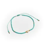 Pulsera elástica con cuentas pequeñas de color turquesa, detalles de cuentas doradas y una perla central.
