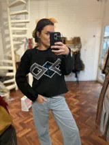 Sweater negro de tejido flexible con apliques geométricos metálicos bordados a mano.