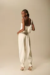Corset estructurado de color blanco marfil (off-white), con inserciones de tejido calado en el escote y finos breteles ajustables. Cuenta con diseño de costuras entalladas y terminación curva en el bajo.