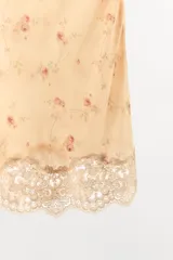Falda mini de tiro medio confeccionada en viscosa, de color beige con delicado estampado de pequeñas flores y detalle de encaje tono sobre tono en el bajo.