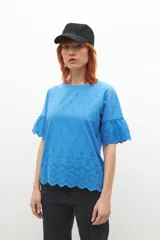 Remera celeste con broderie, de mangas cortas con volados.