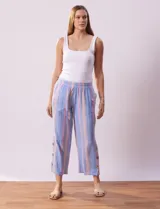 Pantalón de algodón estampado a rayas verticales azules y blancas, marca Erika. Tiene pretina elastizada, bolsillos delanteros, ruedo lateral con tajo y botones decorativos.
