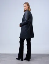 Chaqueta larga de eco cuero color negro, con cuello a la base, abertura central y bolsillos delanteros.