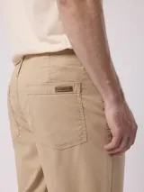 Pantalón de corte recto en color beige, confeccionado en mezcla de algodón y lino, con bolsillos laterales y trabillas para cinturón.