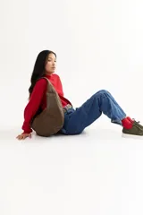 Bolso hobo marrón de cuero con correa al hombro. Diseño minimalista y amplio espacio interior.