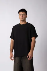 Remera de corte regular confeccionada en una mezcla de rayón y lino con textura entramada. Presenta cuello redondo, mangas cortas y un diseño de inspiración rústica y liviana.