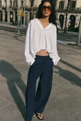 Pantalón barrel color azul marino, de tiro bajo, pernera holgada con diseño redondeado que se estrecha hacia el tobillo, con bolsillos delanteros y cierre frontal.