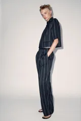 Pantalón de tiro medio de ZARA Woman Collection, confeccionado con mezcla de lino. Presenta diseño de rayas diplomáticas, bolsillos laterales, pinzas en el delantero y cierre frontal con cremallera, botón y ganchos metálicos.