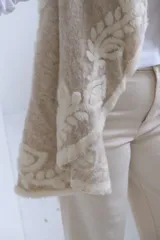 Chaleco abierto de lana en color beige, con diseño de solapas amplias y bordados florales en relieve en tono crema. Posee un corte fluido y sin cierre frontal.
