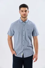 Camisa de manga corta confeccionada en mezcla de lino y algodón, con estampado de cuadros pequeños en tonos azules. Presenta cuello camisero con botones, cierre frontal abotonado, bolsillo aplicado en el pecho y dobladillo redondeado.
