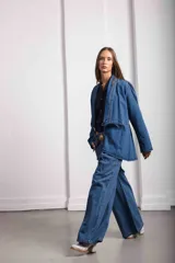 Blazer de denim azul con corte a la cintura, mangas largas con hombros ligeramente abullonados y cierre frontal mediante un botón de guampa.