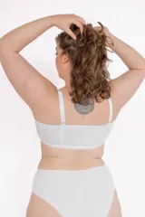 Soutien triangular blanco de algodón elastizado con cierre frontal mediante broche, breteles elásticos regulables y espalda ancha.