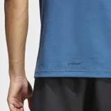 Remera de entrenamiento Adidas con tecnología AEROREADY para absorción de humedad. Presenta cuello redondo, ajuste ceñido, cortes en los dobladillos laterales y dobladillo trasero ligeramente más largo. Incluye el logo de la marca estampado en el centro del pecho.