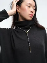 Buzo tejido de cuello alto, con diseño de sisa caída y silueta holgada. Presenta aberturas laterales en el ruedo que aportan movimiento.