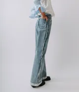 Pantalón de jean estilo wide leg de color azul claro, con costuras laterales deshilachadas, dobladillo ancho vuelto hacia arriba y bolsillos traseros con detalles deshilachados.