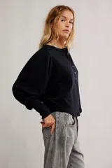 Top de tela con textura tipo gofrado, color negro, con escote redondo, botonadura henley y mangas largas abullonadas con puño.