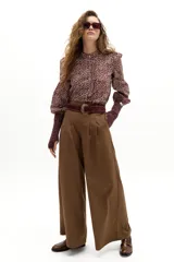 Pantalón culotte color camel con sutiles rayas bordó, de cintura alta y reforzada, con pinzas en la cintura, cierre frontal con gancho y botón interno, y bolsillos laterales. Las piernas son anchas.