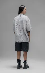 Camisa de manga corta y corte holgado con diseño de bordado broderie en toda la prenda, cuello camisero y cierre frontal de botones.