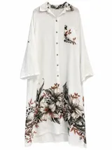 Vestido camisero midi de lino color blanco, con mangas 3/4, cuello camisero, cierre frontal con botones y un bolsillo en el pecho. Presenta un estampado floral en tonos marrones y verdes en el ruedo, el bolsillo y el interior del cuello.