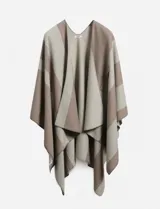 Capa tipo ruana de tejido grueso, con diseño de bloques de color en tonos beige y marrón topo, con cuello en V y caída asimétrica.