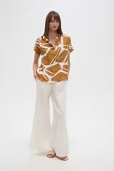 Blusa holgada de manga corta, con escote en V y estampado abstracto en tonos verde oliva y blanco.