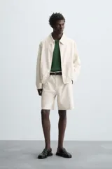 Bermuda de algodón color beige claro con rayas verticales finas en tono más oscuro. Diseño de corte regular con bolsillos delanteros y bolsillos traseros de plastrón.