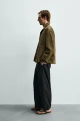 Sobrecamisa relaxed fit de piel con acabado en ante de color verde militar, con cuello solapa, manga larga con puño abotonado, bolsillos de vivo en la cadera y cierre frontal con botones.