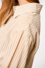 Camisa a rayas verticales grises y blancas, de corte recto y mangas largas.