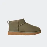 Botas de caña baja UGG modelo Classic Ultra Mini, confeccionadas en piel de oveja con acabado de gamuza. Presentan una línea superior asimétrica, costuras con detalle de puntada overlock, lengüeta trasera y suela de goma flexible.