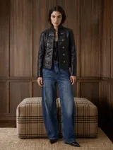 Chaqueta de cuero vacuno negro con cuello alto, diseño de inspiración militar de doble botonadura con botones metálicos dorados y mangas largas.