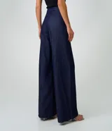 Pantalón wide leg de jean azul oscuro, de talle alto con pretina estructurada, pinzas frontales, sobreposición cruzada y piernas amplias.