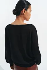 Jersey de punto fino negro con escote en V profundo y manga larga con puños ajustados.