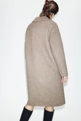 Abrigo largo de lana con diseño cruzado, cuello de solapa, manga larga y bolsillos delanteros de plastrón. Cierre frontal con botones.