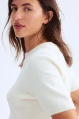 Buzo de punto fino suave con cuello redondo y manga corta. Presenta terminaciones acanaladas en el cuello, puños y bajo.