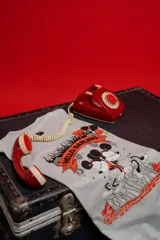 Remera de algodón premium color gris claro, corte oversize, con cuello redondo y manga corta. Presenta un estampado frontal pequeño con dos personajes de Disney (Mickey y Minnie) en llamas con el texto "THE FLAME OF LOVE".