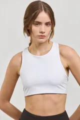 Top deportivo corto de sujeción media, con escote redondo clásico y espalda abierta. Presenta un diseño al cuerpo con elástico interno en la cintura.