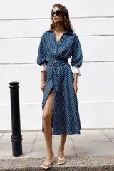 Vestido midi azul marino con rayas blancas, cuello solapa, escote en V y cierre frontal con botones. Cuenta con mangas abullonadas por debajo del codo con puños anchos a contraste, cinturón ajustable del mismo tejido con hebilla metálica y falda evasé.