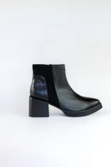 Bota corta de cuero negro con paneles laterales de gamuza y cuero texturizado. Tiene taco geométrico y punta cuadrada.