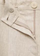 Pantalón de lino color beige, de corte recto y largo cropped, con cintura elástica, trabillas y cierre frontal con cremallera y botón.